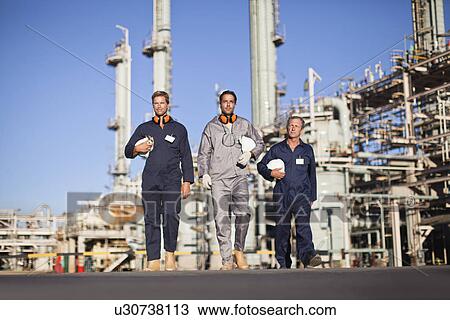 Stock Image - Workers walking at oil refinery. Fotosearch