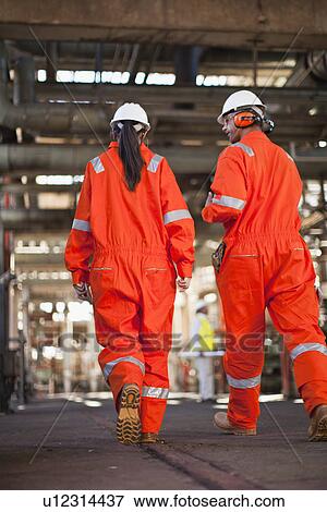 Stock Photo - Workers walking at oil refinery. Fotosearch