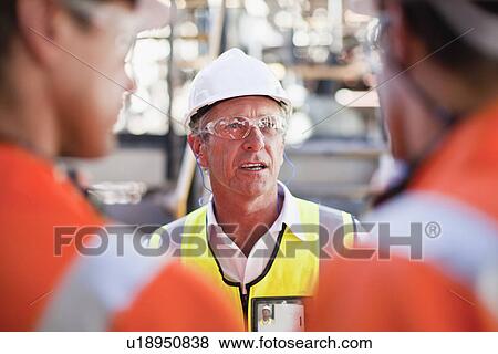 Stock Photo - Workers walking at oil refinery. Fotosearch