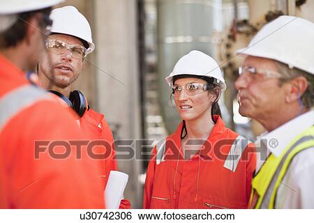 Stock Photograph - Workers walking at oil refinery. Fotosearch