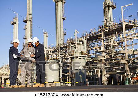 Picture - Workers with blueprints at oil refinery. Fotosearch