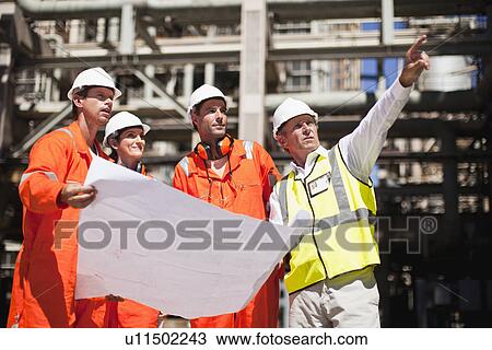 Workers with blueprints at oil refinery View Large Photo Image Stock Image - Workers with blueprints at oil refinery. Fotosearch
