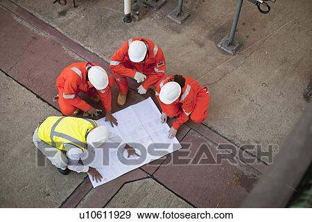 Stock Photo - Workers with blueprints at oil refinery. Fotosearch