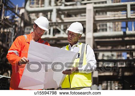 Stock Photo - Workers with blueprints at oil refinery. Fotosearch