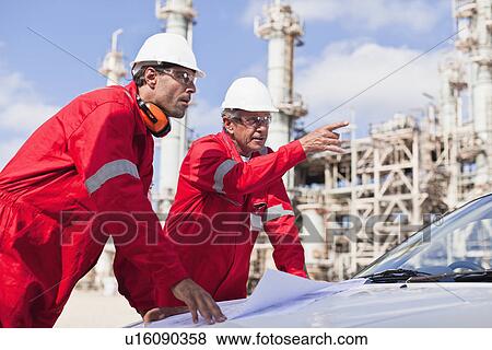 Stock Photo - Workers with blueprints at oil refinery. Fotosearch