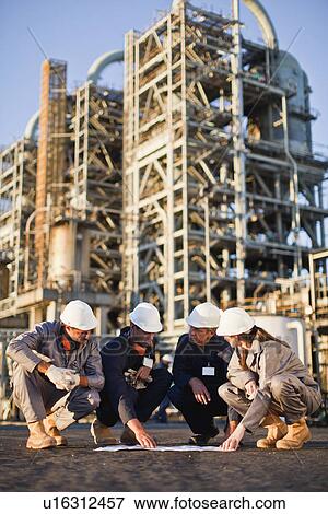 Stock Photo - Workers with blueprints at oil refinery. Fotosearch