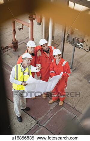 Stock Photography - Workers with blueprints at oil refinery. Fotosearch