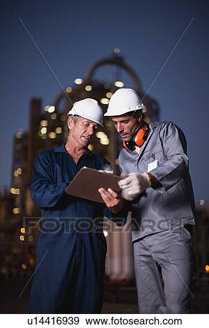 Workers with clipboard at oil refinery View Large Photo Image Stock Photo - Workers with clipboard at oil refinery. Fotosearch