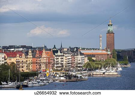 Stock Image - Boats at a harbor with buildings at the waterfront, Stockholm Town Hall, Riddarfjarden, Stockholm, Sweden. Fotosearch