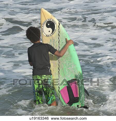 Boy carrying a surfboard in the sea, Sayulita, Nayarit, Mexico View Large Photo Image Stock Photograph - Boy carrying a surfboard in the sea, Sayulita, Nayarit, Mexico. Fotosearch