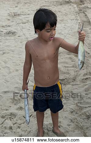 Stock Image - Boy holding fish in both hands, Sayulita, Nayarit, Mexico. Fotosearch