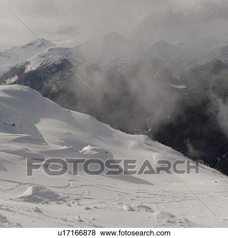 Stock Photo - Clouds over snow covered mountains, Whistler, British Columbia, Canada. Fotosearch