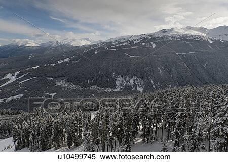 Stock Photography - Clouds over snow covered mountains, British Columbia, Canada. Fotosearch