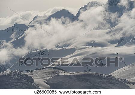 Stock Photography - Clouds over snowcapped mountains, Whistler, British Columbia, Canada. Fotosearch
