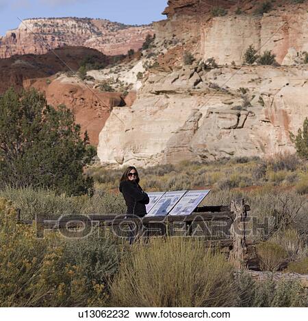 Stock Image - Female tourist standing in a desert near guide maps, Paria Canyon, Paria, Kane County, Utah, USA. Fotosearch