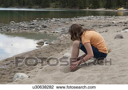 Stock Image - Girl playing with sand at the lakeside, Edith Lake, Jasper National Park, Alberta, Canada. Fotosearch