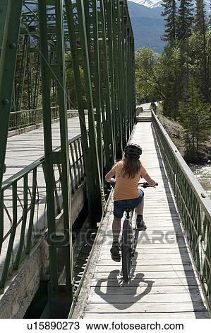 Girl riding a bicycle on a bridge over Athabasca River, Jasper National Park, Alberta, Canada View Large Photo Image Stock Image - Girl riding a bicycle on a bridge over Athabasca River, Jasper National Park, Alberta, Canada. Fotosearch