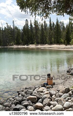 Stock Photograph - Girl sitting at the lakeside, Edith Lake, Jasper National Park, Alberta, Canada. Fotosearch