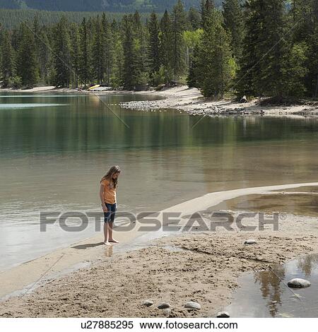 Stock Photography - Girl sitting at the lakeside, Edith Lake, Jasper National Park, Alberta, Canada. Fotosearch