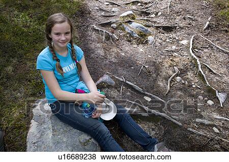 Stock Photo - Girl sitting on a rock, Maligne Lake, Jasper National Park, Alberta, Canada. Fotosearch