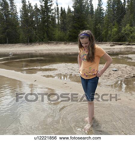 Stock Photograph - Girl soaking her feet in the shallow water of Edith Lake, Jasper National Park, Alberta, Canada. Fotosearch