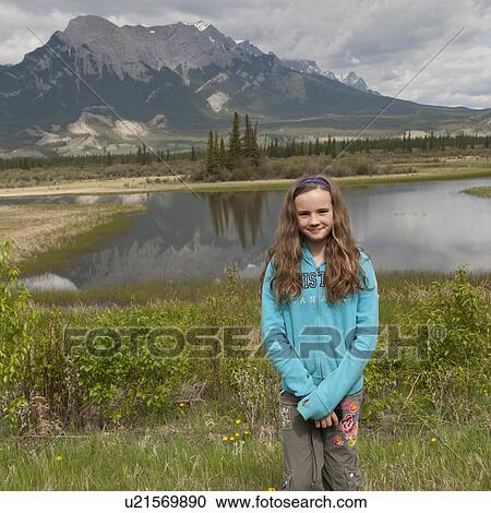 Girl standing near a lake with mountains in the background, Jasper National Park, Alberta, Canada View Large Photo Image Stock Image - Girl standing near a lake with mountains in the background, Jasper National Park, Alberta, Canada. Fotosearch