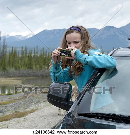 Stock Image - Girl taking picture from the window of a car, Jasper National Park, Alberta, Canada. Fotosearch