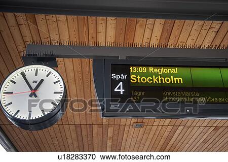 Stock Image - Low angle view of a clock with sign at a station, Uppsala, Sweden. Fotosearch