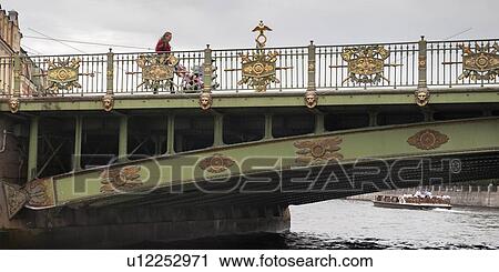 Stock Image - Low angle view of a woman crossing the Panteleimonovsky Bridge, Fontanka River, St. Petersburg, Russia. Fotosearch