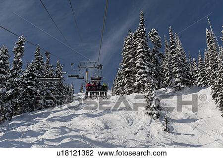 Stock Image - Low angle view of skiers on ski lifts, Symphony Amphitheatre, Whistler, British Columbia, Canada. Fotosearch