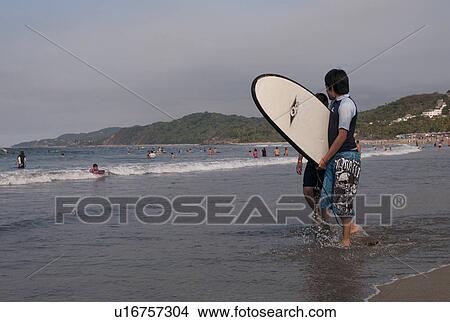 Picture - Man carrying surfboard on the beach, Sayulita, Nayarit, Mexico. Fotosearch