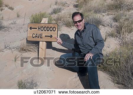 Stock Image - Man pointing at a signboard, Amangiri, Canyon Point, Hoodoo Trail, Utah, USA. Fotosearch