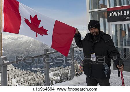 Man showing Canadian flag at a ski resort, Whistler, British Columbia, Canada View Large Photo Image Picture - Man showing Canadian flag at a ski resort, Whistler, British Columbia, Canada. Fotosearch