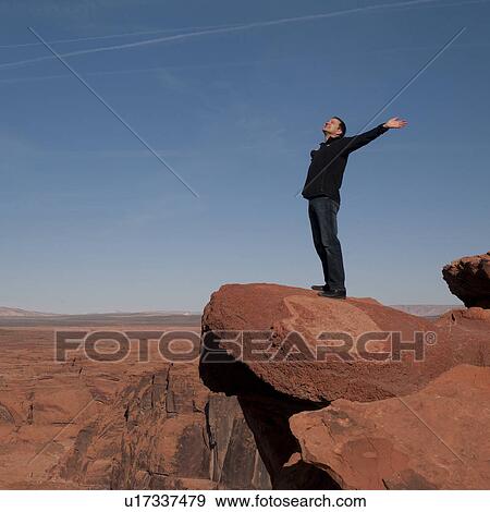 Stock Photo - Man standing on a rock with his arms outstretched, Horseshoe Bend, Glen Canyon National Recreation Area, Arizona-Utah, USA. Fotosearch