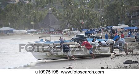 Stock Photo - People pushing a boat into the sea, Sayulita, Nayarit, Mexico. Fotosearch