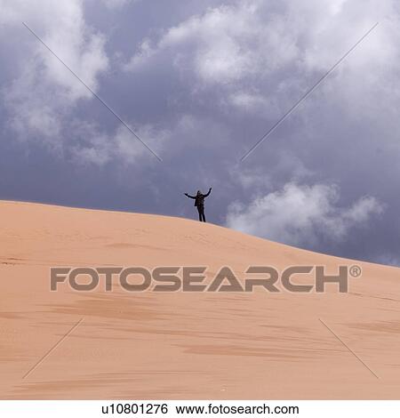 Person standing in a desert with arms raised, Coral Pink Sand Dunes State Park, Utah, USA View Large Photo Image Stock Photograph - Person standing in a desert with arms raised, Coral Pink Sand Dunes State Park, Utah, USA. Fotosearch