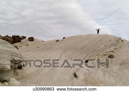 Stock Image - Person standing on a rock with arms outstretched, Amangiri, Canyon Point, Hoodoo Trail, Utah, USA. Fotosearch
