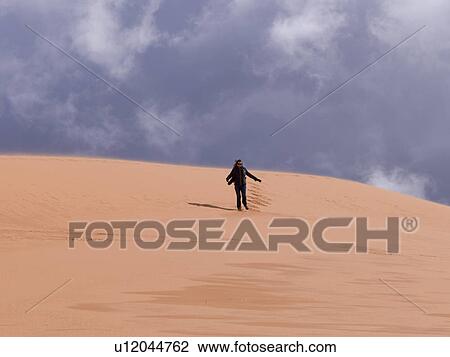 Stock Image - Person walking in a desert, Coral Pink Sand Dunes State Park, Utah, USA. Fotosearch