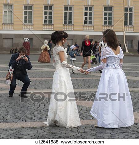 Stock Photo - Photographer taking picture of a bride and bridesmaid, Palace Square, St. Petersburg, Russia. Fotosearch