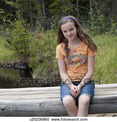 Stock Image - Portrait of a girl sitting on a log bridge, Edith Lake, Jasper National Park, Alberta, Canada. Fotosearch