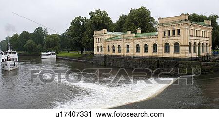 Stock Image - Pump house at the riverside with boats in the river, Fyris River, Uppsala, Sweden. Fotosearch