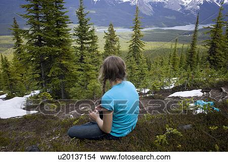 Picture - Rear view of a girl sitting with Maligne Lake in the background, Bald Hills Trail, Jasper National Park, Alberta, Canada. Fotosearch