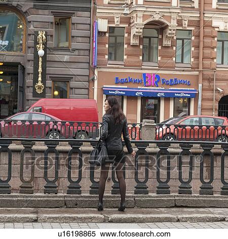 Stock Photography - Rear view of a woman looking at traffic in a city, Griboyedov Canal, St. Petersburg, Russia. Fotosearch