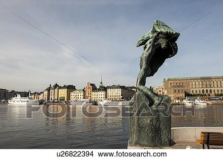 Picture - Sculpture at waterfront with buildings in the background, Gamla Stan, Stockholm, Sweden. Fotosearch