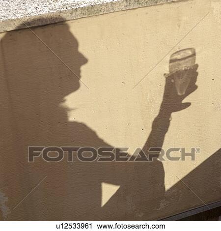 Stock Image - Shadow of a person holding a wine glass, Stockholm, Sweden. Fotosearch