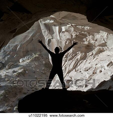 Stock Photography - Silhouette of a man standing with arms raised in Ulrike's Cave, Amangiri, Canyon Point, Utah, USA. Fotosearch