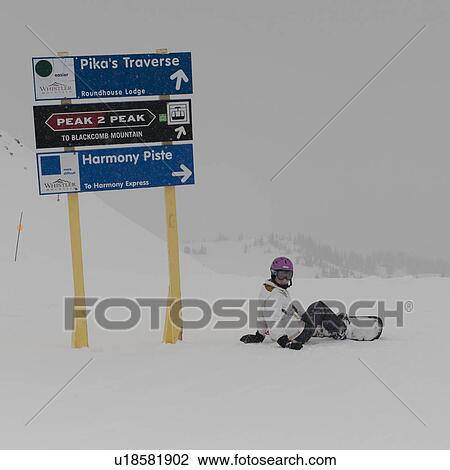 Stock Image - Snowboarder fallen down near directional signs, Whistler, British Columbia, Canada. Fotosearch