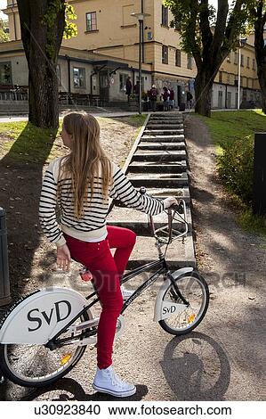 Stock Image - Teenage girl cycling on a street, Skeppsholmen, Stockholm, Sweden. Fotosearch