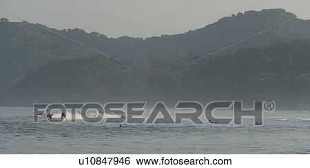 Stock Photograph - Tourists enjoying surfing in the sea, Sayulita, Nayarit, Mexico. Fotosearch