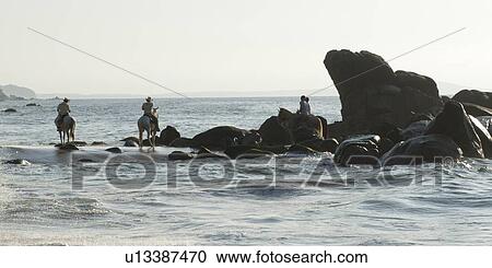 Stock Image - Tourists riding horses on the coast, Sayulita, Nayarit, Mexico. Fotosearch